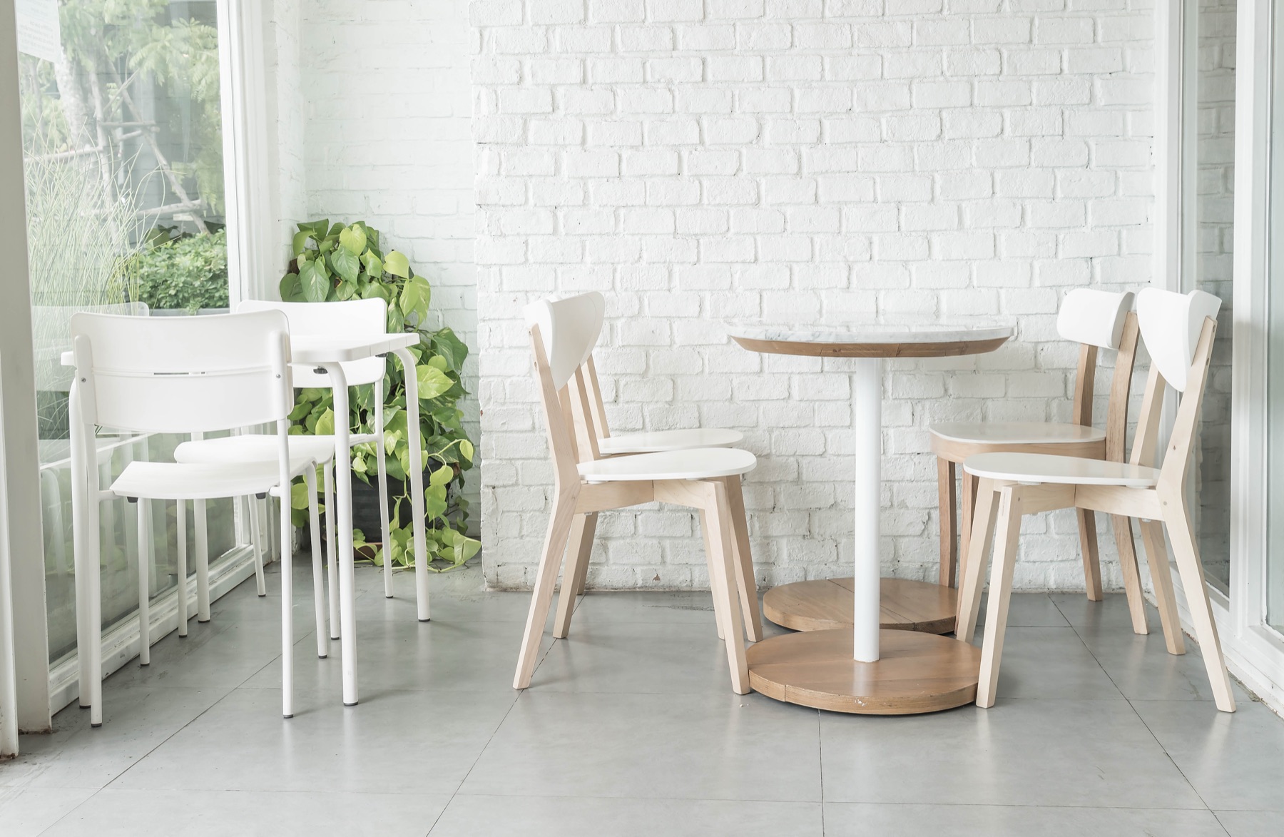 A bright cafe corner with white brick walls — a TV above the table running a split-flap quote board